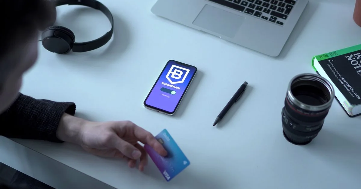 Personne tenant une carte de crédit via une application de monnaie numérique, explorant la technologie blockchain.