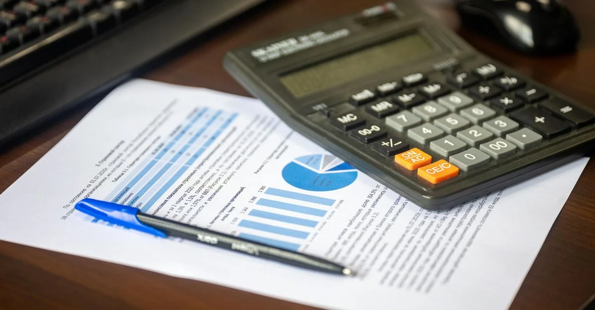 Bureau avec calculatrice, rapport financier et stylo, suggérant une analyse commerciale.