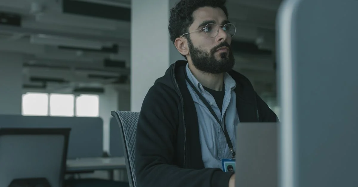 Homme avec des lunettes travaillant à un bureau dans un cadre de bureau, concentré et engagé.