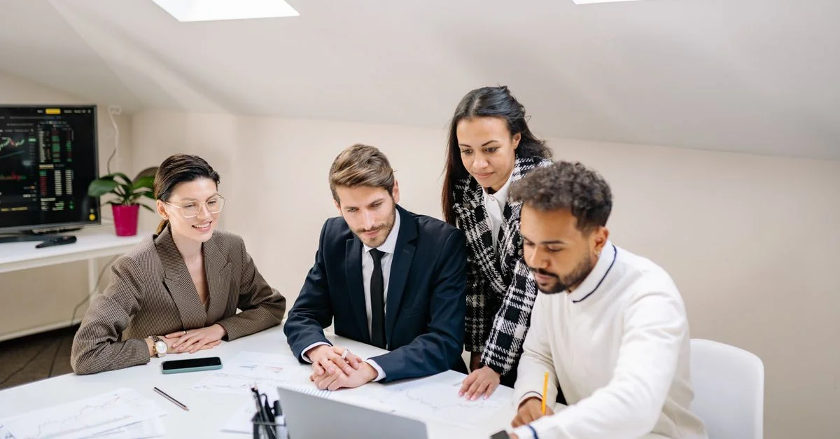 Une équipe diversifiée de professionnels collaborant et discutant du travail dans un environnement de bureau moderne.