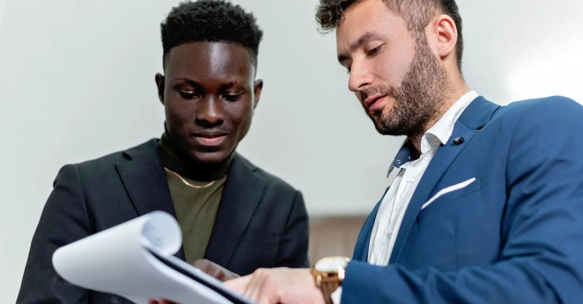 Deux hommes d'affaires en costume discutent de documents importants dans un cadre de bureau.