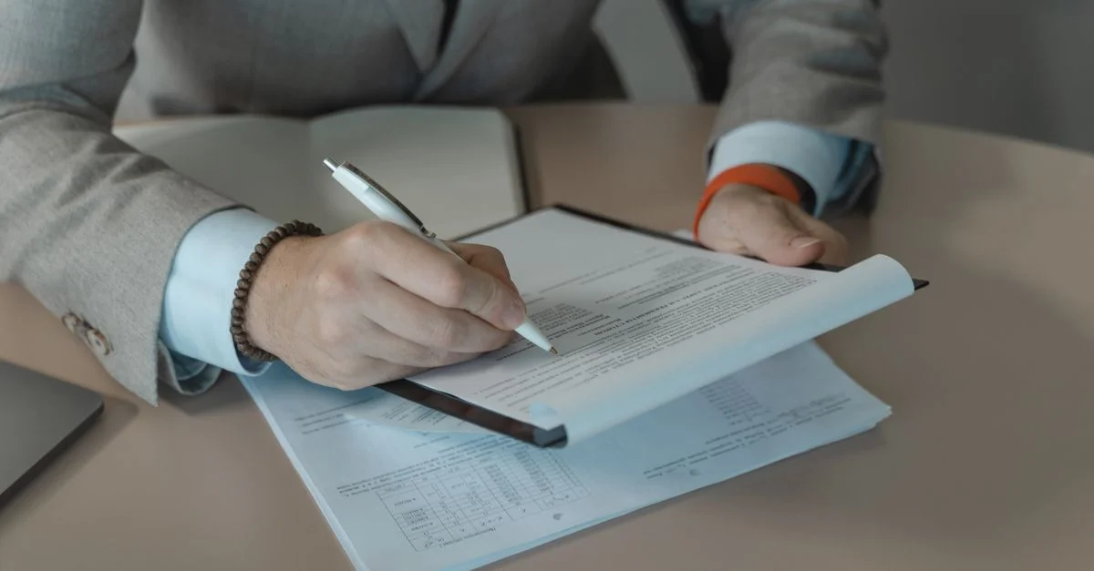 Gros plan sur une personne d'affaires signant des documents à un bureau avec un stylo.