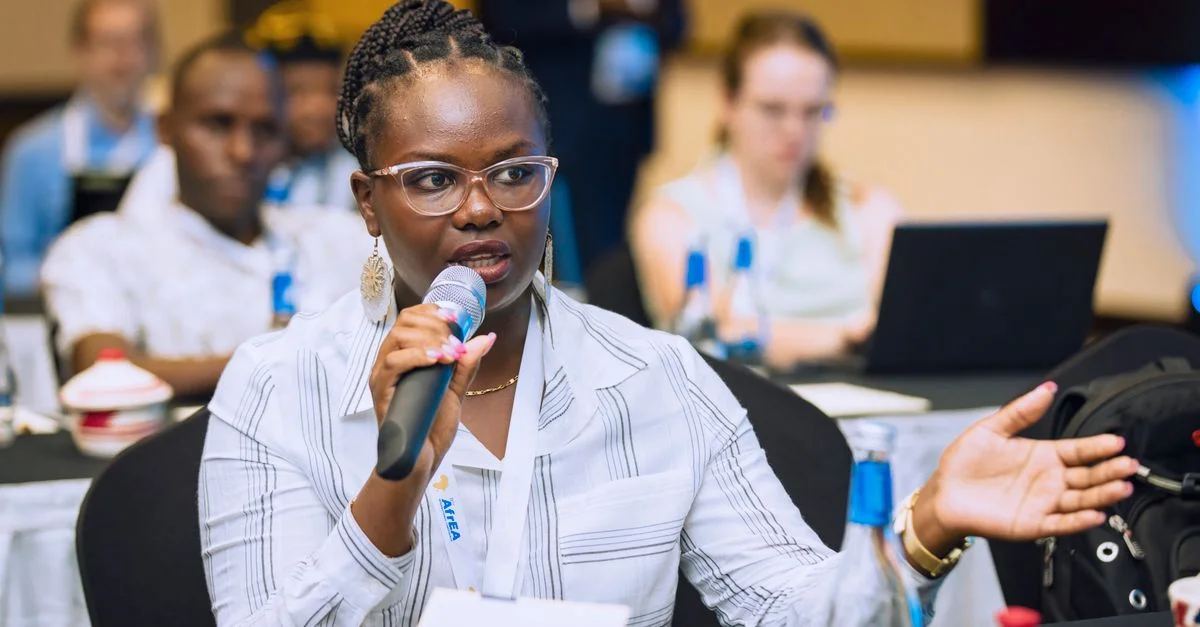 Femme parlant dans un microphone lors d'une conférence d'affaires, interagissant avec le public.
