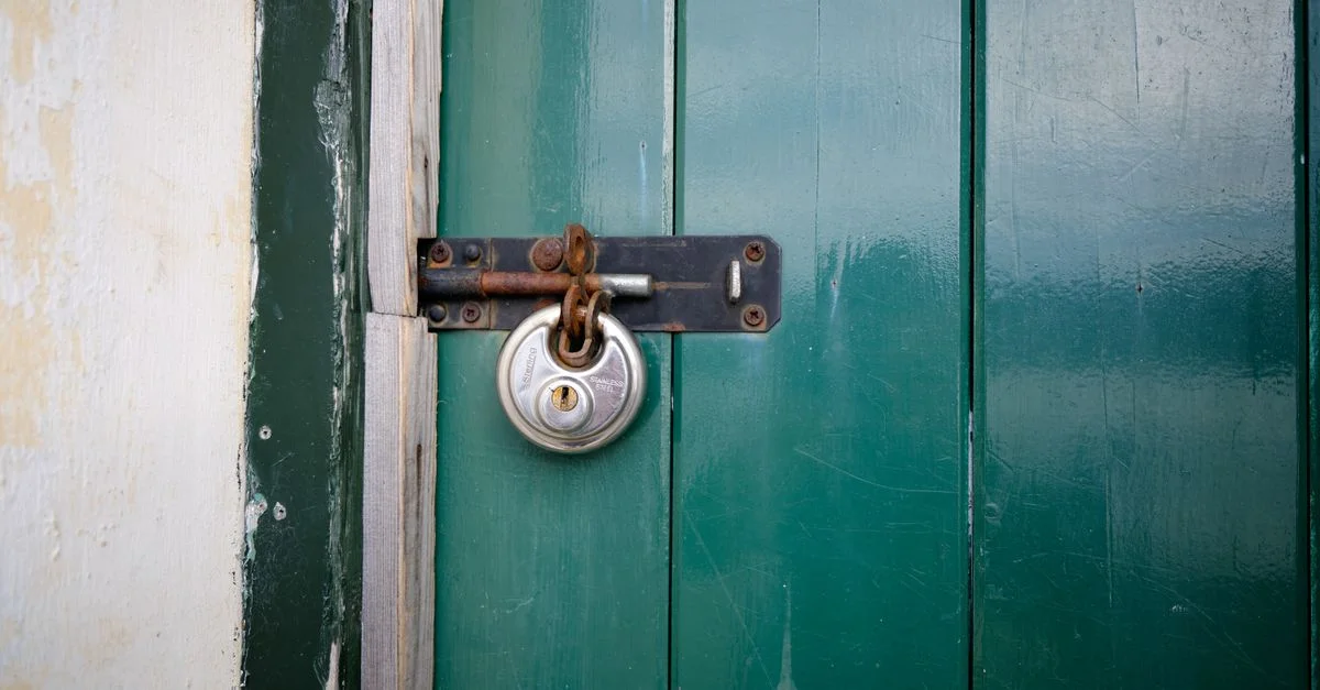 Gros plan sur une porte en bois verte verrouillée avec un cadenas métallique à Keswick, Angleterre.