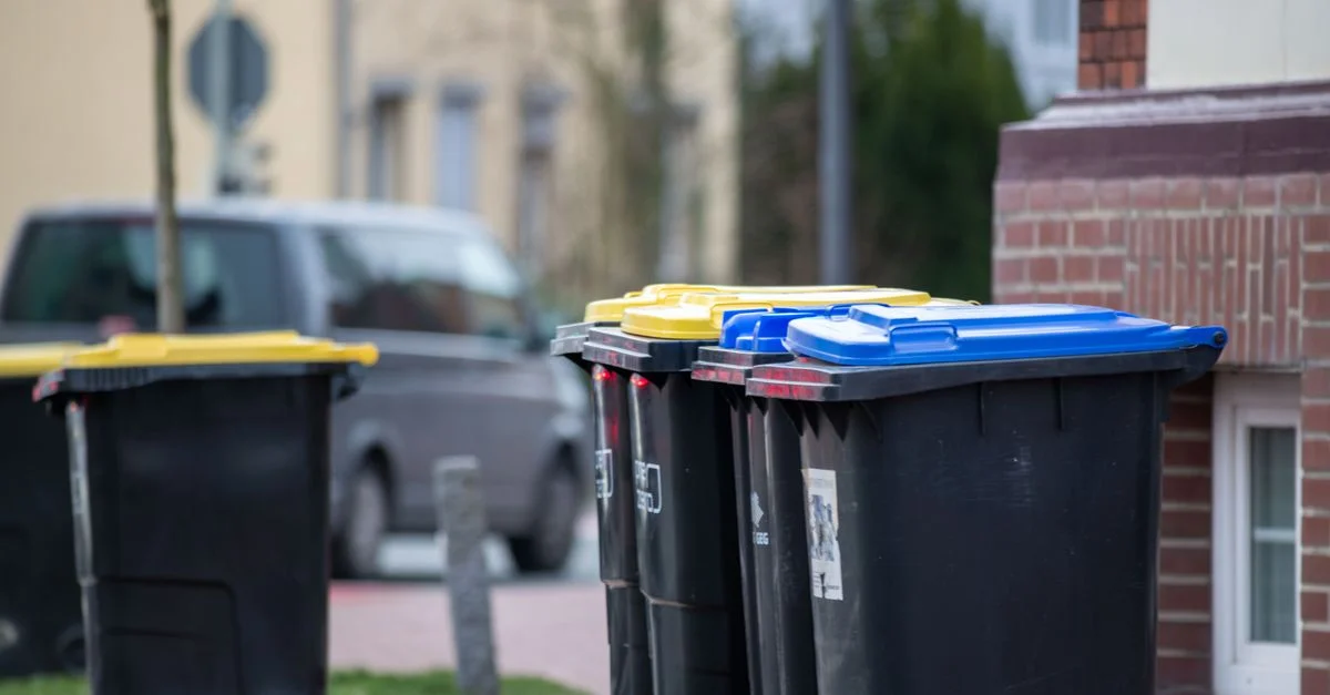 Poubelles codées par couleur dans une rue de la ville à Gütersloh, en Allemagne, illustrant la gestion des déchets urbains.