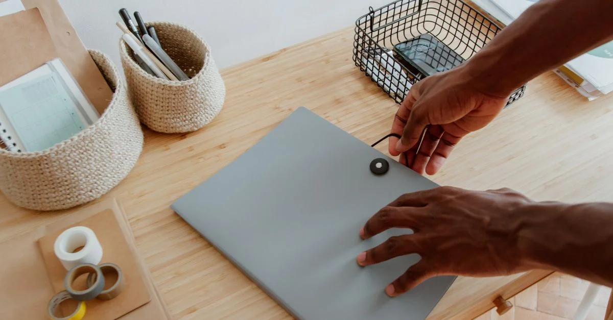 Bureau avec des mains organisant des documents, des fournitures et des essentiels technologiques.